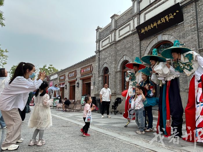 ↑   图为游客在好南关街区与高跷艺人合影留念。资料图片